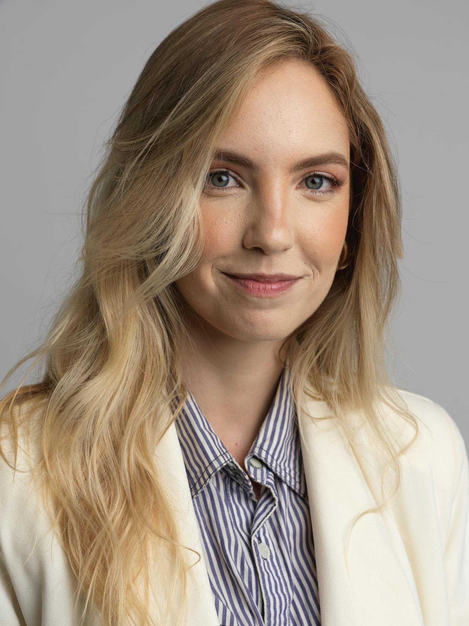Portrait of a confident young woman in business attire with a neutral background.