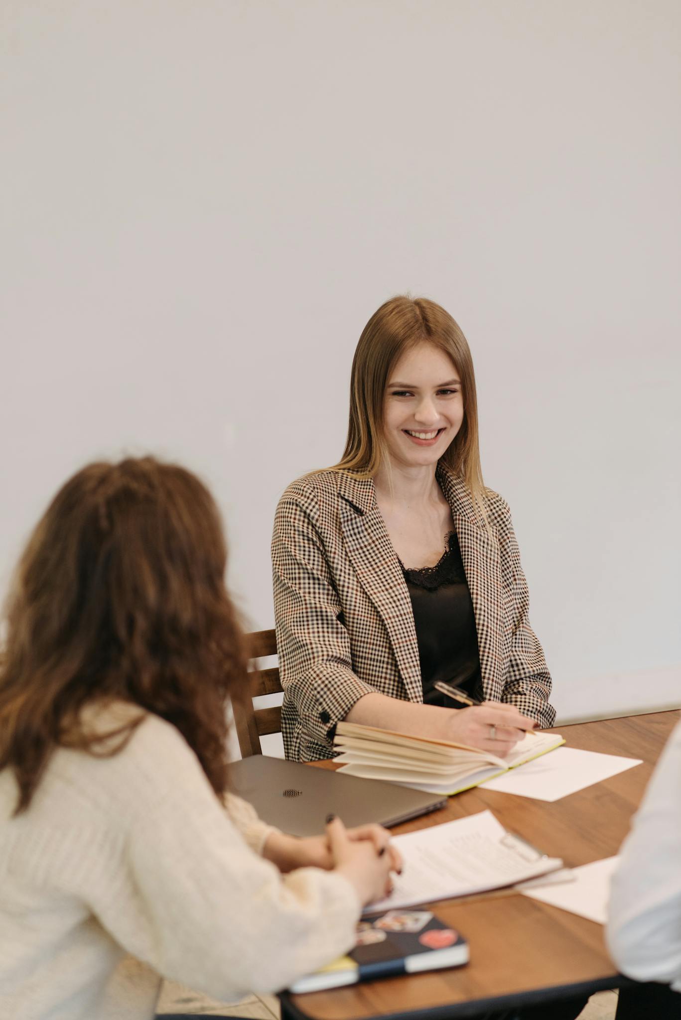 Two women working together at an office table, engaging in a collaborative meeting.